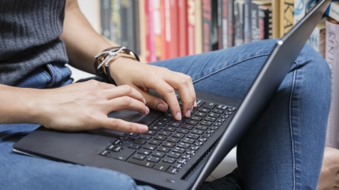 Kvinde sidder med sin laptop på skødet